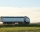 Semi-truck with tipping cargo trailer transporting sand from quarry driving on highway hauling goods in evening. Delivery transportation and logistics concept.